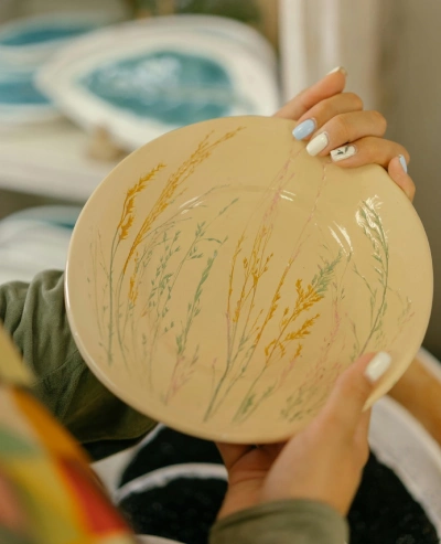 Woman showing painted plate after firing
